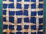 une photo d'une écharpe carrée bleue et marron suspendue à un portant à vêtements