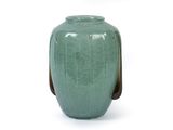 un vase vert avec une anse marron sur fond blanc