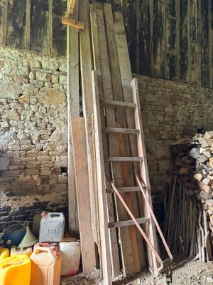 une échelle appuyée contre un mur, à côté d'un tas de bois
