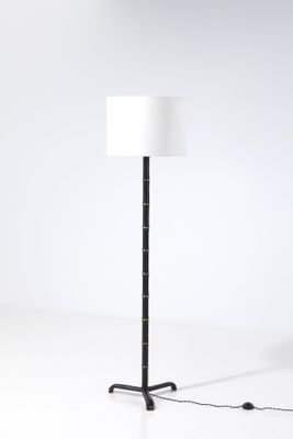 le lampadaire est muni d'un abat-jour blanc et d'un pied noir