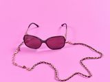 a pair of sunglasses on a chain on a pink background