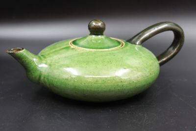 une théière verte posée sur une table