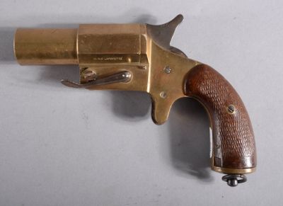 un vieux revolver en laiton avec une crosse en bois, posé sur une surface blanche
