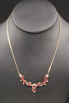 a gold necklace with red and white flowers on a mannequin