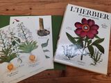 deux livres posés sur une table, sur laquelle se trouvent des fleurs et des plantes
