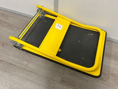 un gros plan d'un chariot à bagages jaune et noir posé sur un plancher en bois