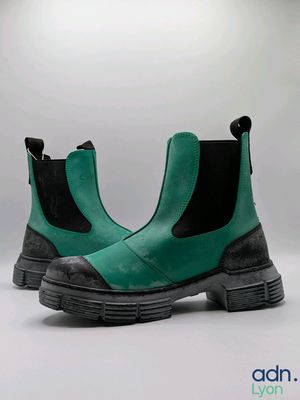 des bottes vertes avec des semelles noires et des bords noirs sur fond blanc