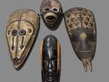 four african masks are arranged in a circle on a gray surface