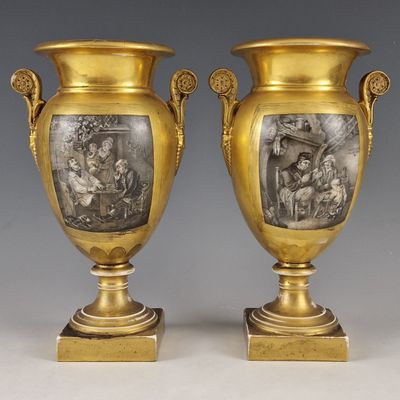 deux vases en or ornés de représentations de personnes, posés sur des socles