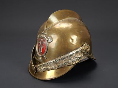 un vieux casque de pompier orné d'un insigne rouge