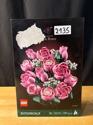 pink roses in a box on a table with a black background