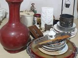 un vase rouge posé sur une table, à côté d'une pile d'assiettes