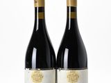 two bottles of wine sitting next to each other on a white surface