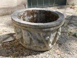 une jardinière en pierre posée au milieu d'une surface en gravier