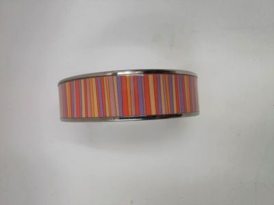 un gros plan d'une bague à rayures colorées posée sur une surface blanche