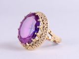 an image of a gold ring with a purple stone in the center