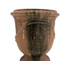 un vase brun posé sur une surface blanche