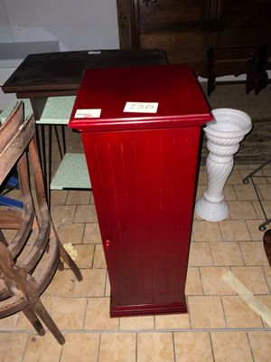 une armoire rouge posée par terre à côté d'une chaise