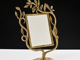 gold leafy mirror on a stand on a white surface