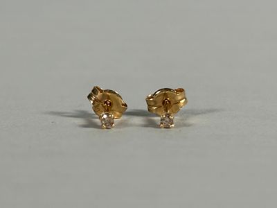 a pair of gold and diamond earrings on a white surface