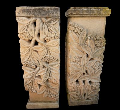 pair of carved stone pedestals with flowers and leaves on them