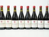 six bouteilles de vin rouge alignées sur une surface blanche