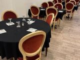 des tables et des chaises disposées dans une longue pièce où est accroché un tableau au mur