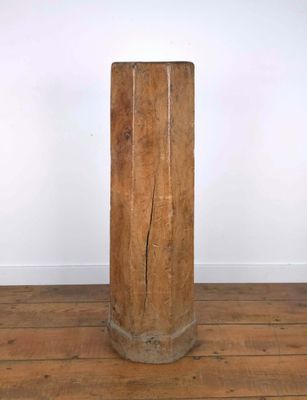 une vieille colonne en bois posée sur un parquet en bois dur