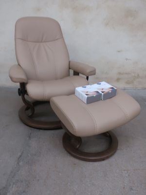a reclining chair with a book on it and a box of books on the ottoman