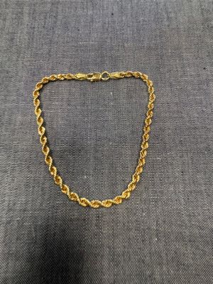 un collier à chaîne en or avec un maillon sur fond gris
