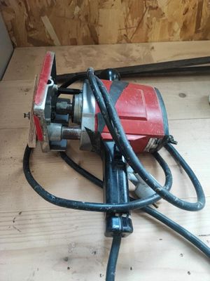 une photo d'une perceuse électrique rouge et noire posée sur un plancher en bois