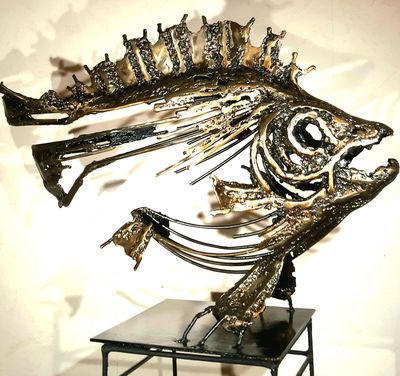 une sculpture de poisson en métal posée sur un socle