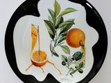 a black and white plate with oranges and leaves on it
