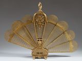 an ornate gold plated fan with a bird on top of it