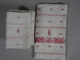 two white towels with red designs on them sitting next to each other