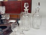 bottles and glasses are sitting on a table next to a wooden tray