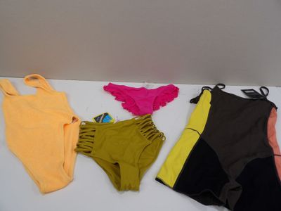 several different colored swimsuits laid out on a white surface