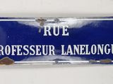 blue and white street sign on a white wall in a french language
