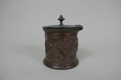 une image représentant un petit pot marron muni d'un couvercle, posé sur une surface blanche