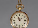 a gold pocket watch with roman numerals on the face