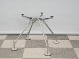 a small metal table with four legs on a checkered floor