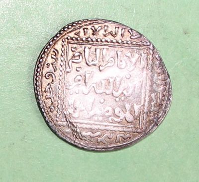 an old silver coin sitting on top of a green surface