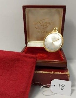 une montre en or posée dans un coffret rouge recouvert d'un tissu rouge