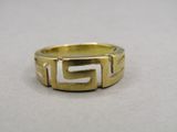 un gros plan d'une bague en or ornée d'un motif grec