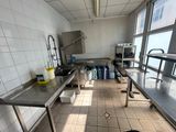 des tables et des bancs dans une cuisine équipée d'un évier et d'une grande fenêtre