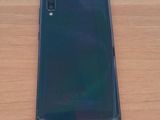 a close up of the back of a black phone on a wooden table