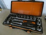 un jeu d'outils rangé dans une boîte à outils posée par terre