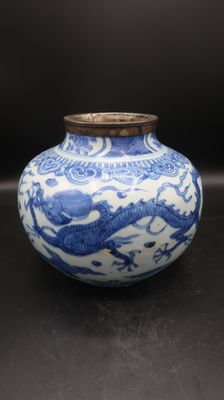 un vase bleu et blanc posé sur une surface noire