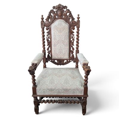 an antique carved chair with upholstered back and arms