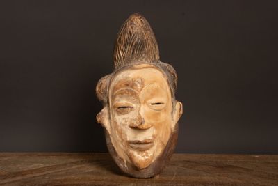 sculpture en bois représentant le visage d'un homme, posée sur une table en bois